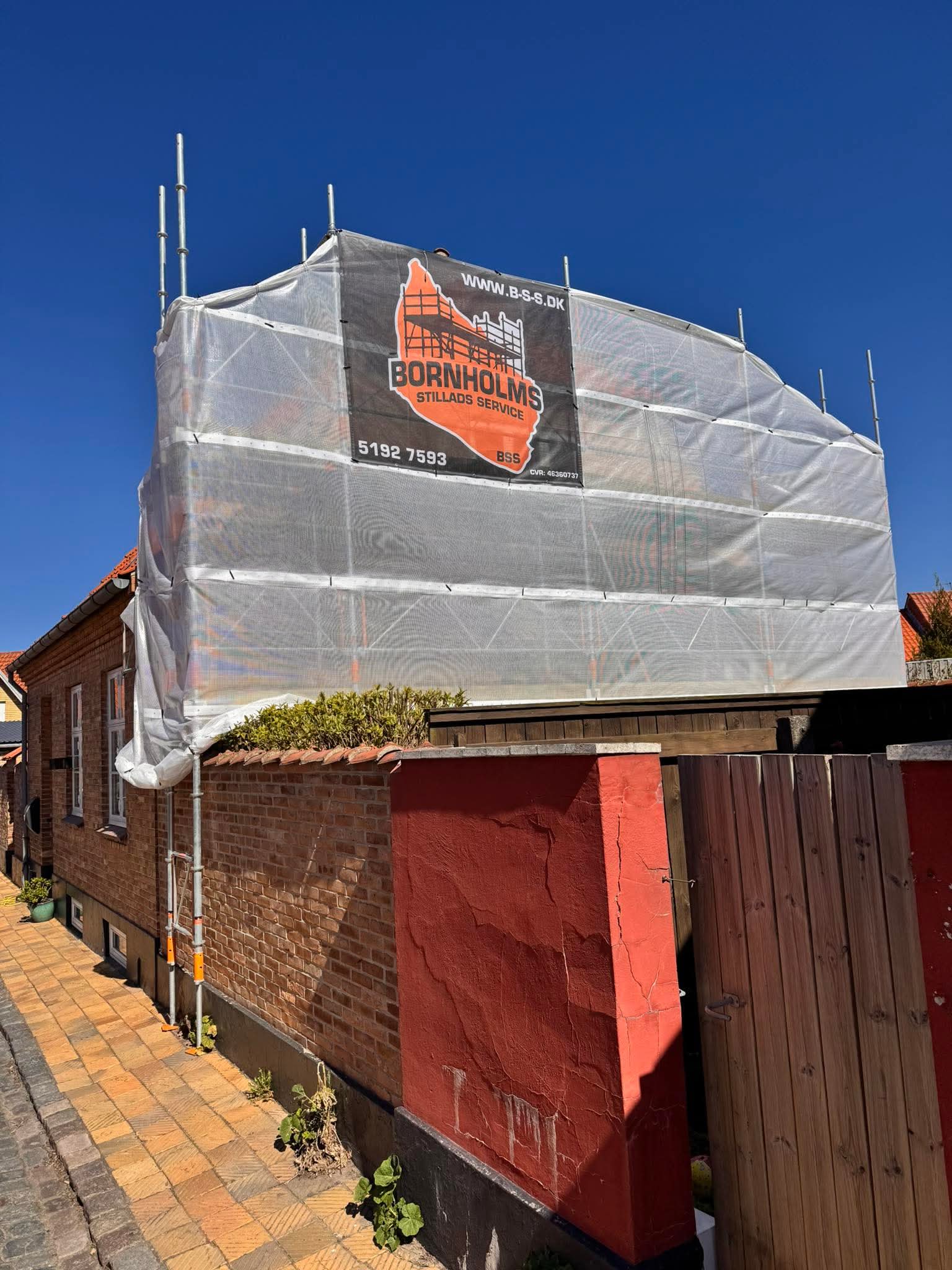 Indpakket stillads med totaloverdækning og BSS-banner på Bornholm